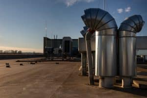 External unit of commercial air conditioning and ventilation system installed on industrial building roof. Exhaust vent on flat factory rooftop