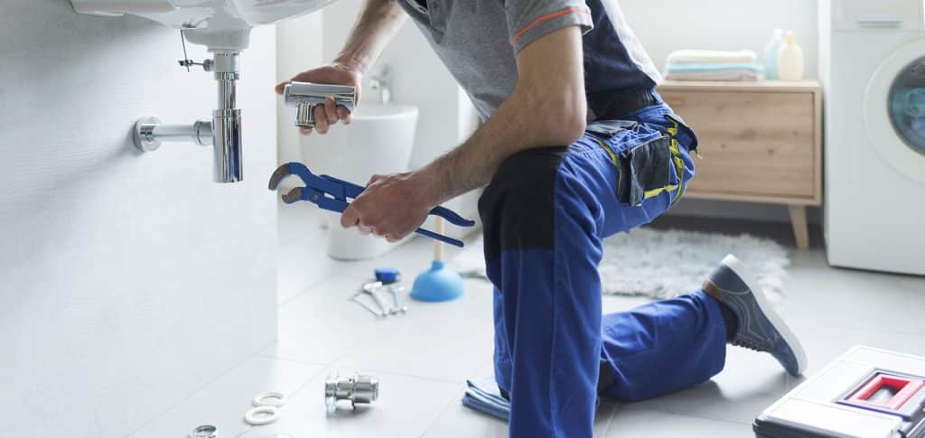 Professional plumber replacing sink pipes to meet Florida plumbing code requirements