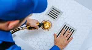 Plumber using hydro jet drain cleaning equipment