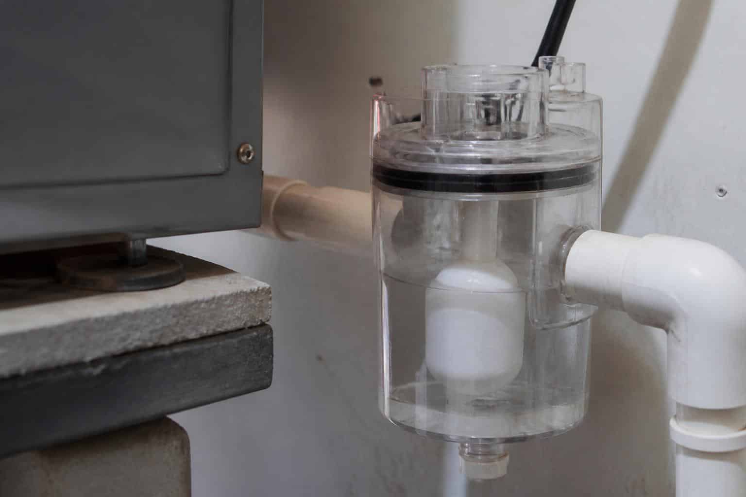 Condensate float switch installed on the PVC drain line beside a residential air handler