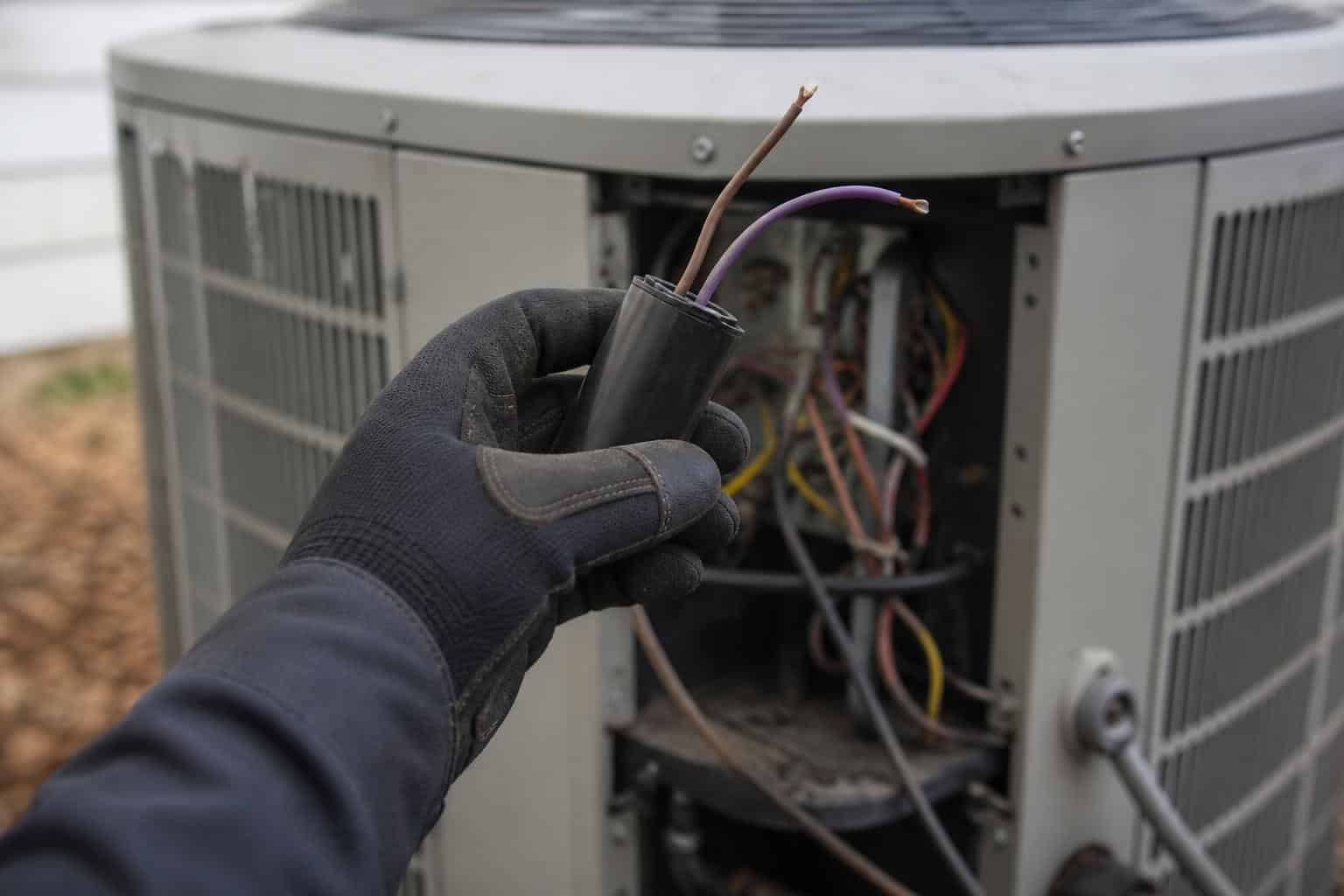 Multimeter measuring capacitance of a round run capacitor from an outdoor air conditioning unit