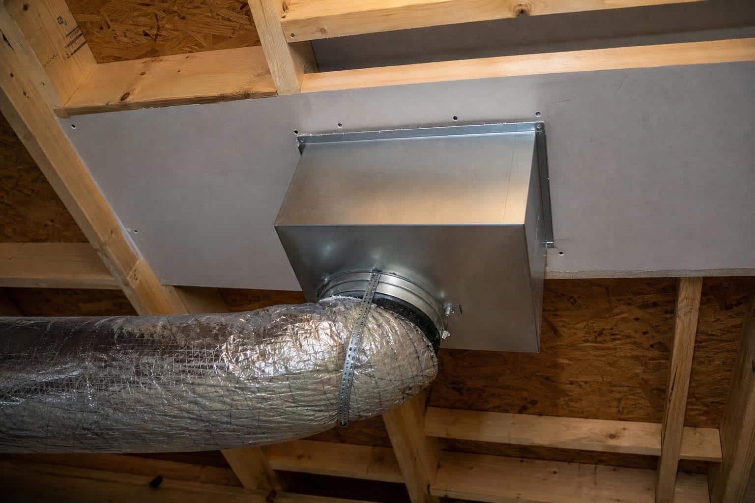 Sheet-metal duct boot connected to flex duct above a ceiling register in an attic