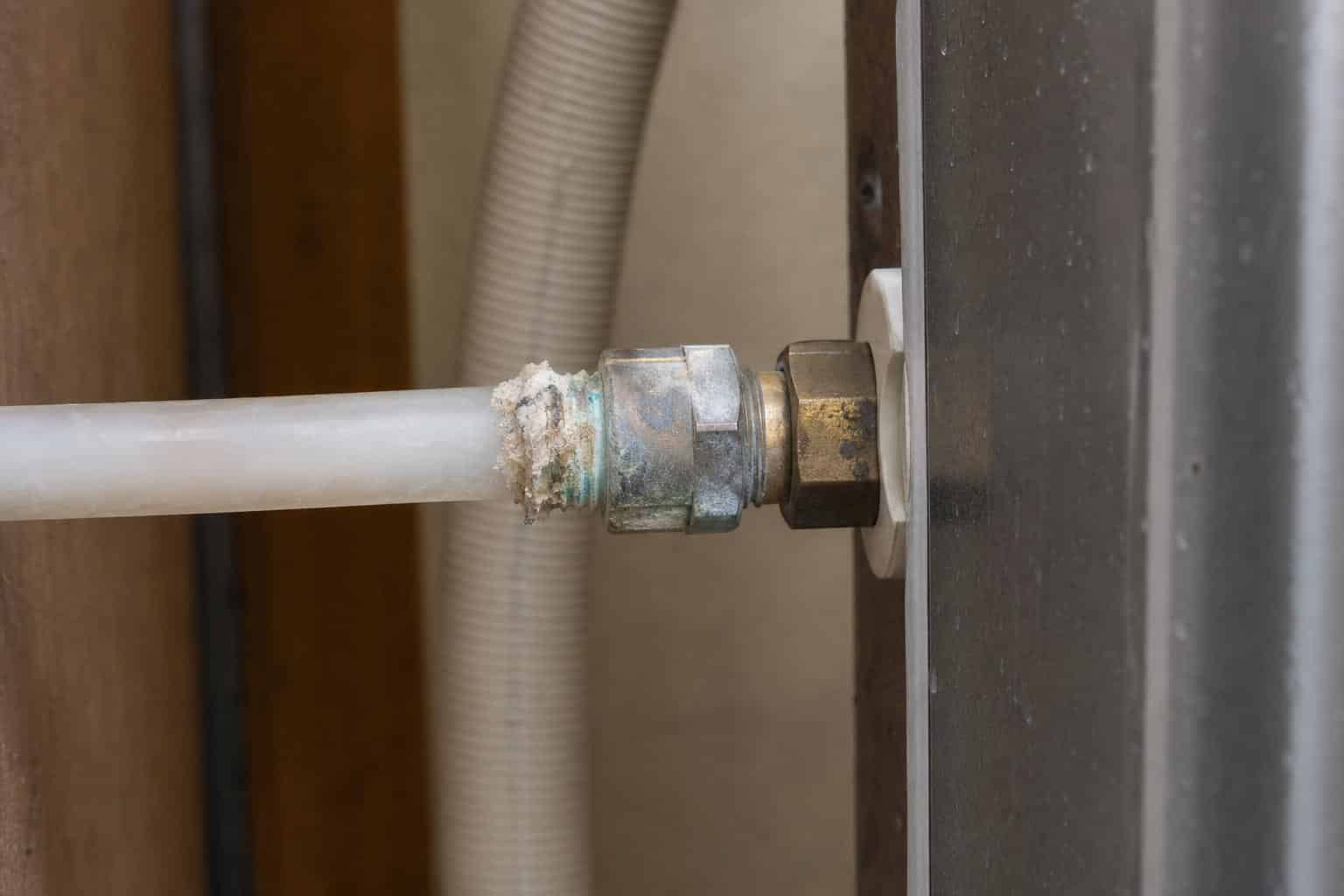 Close-up of polyethylene refrigerator supply line with mineral deposits at compression fitting