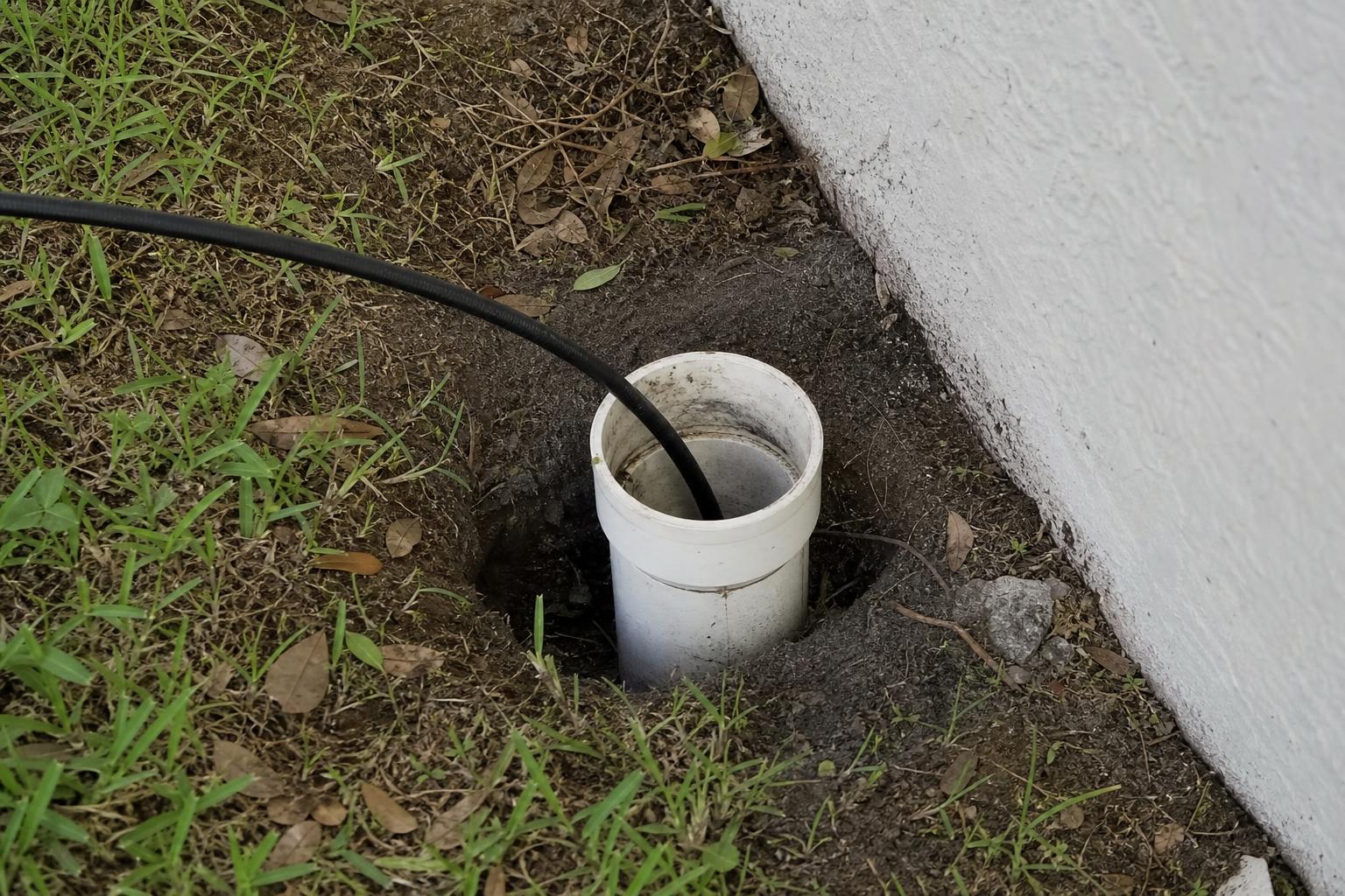 Sewer inspection camera cable entering an exterior residential cleanout in Florida