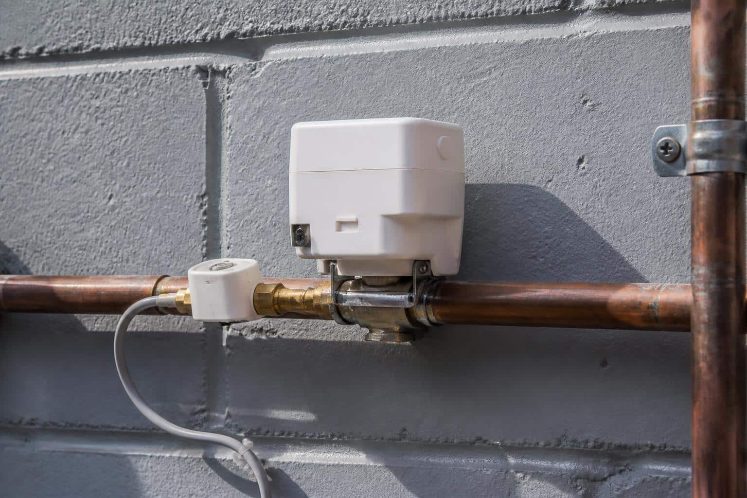 Smart water shutoff valve installed on the main supply line beside a Florida home exterior wall