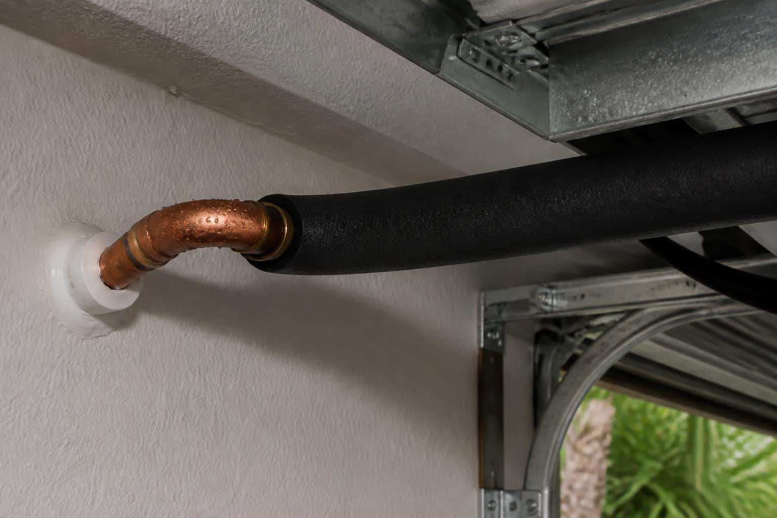 Foam pipe insulation being fitted over a cold copper water line in a garage