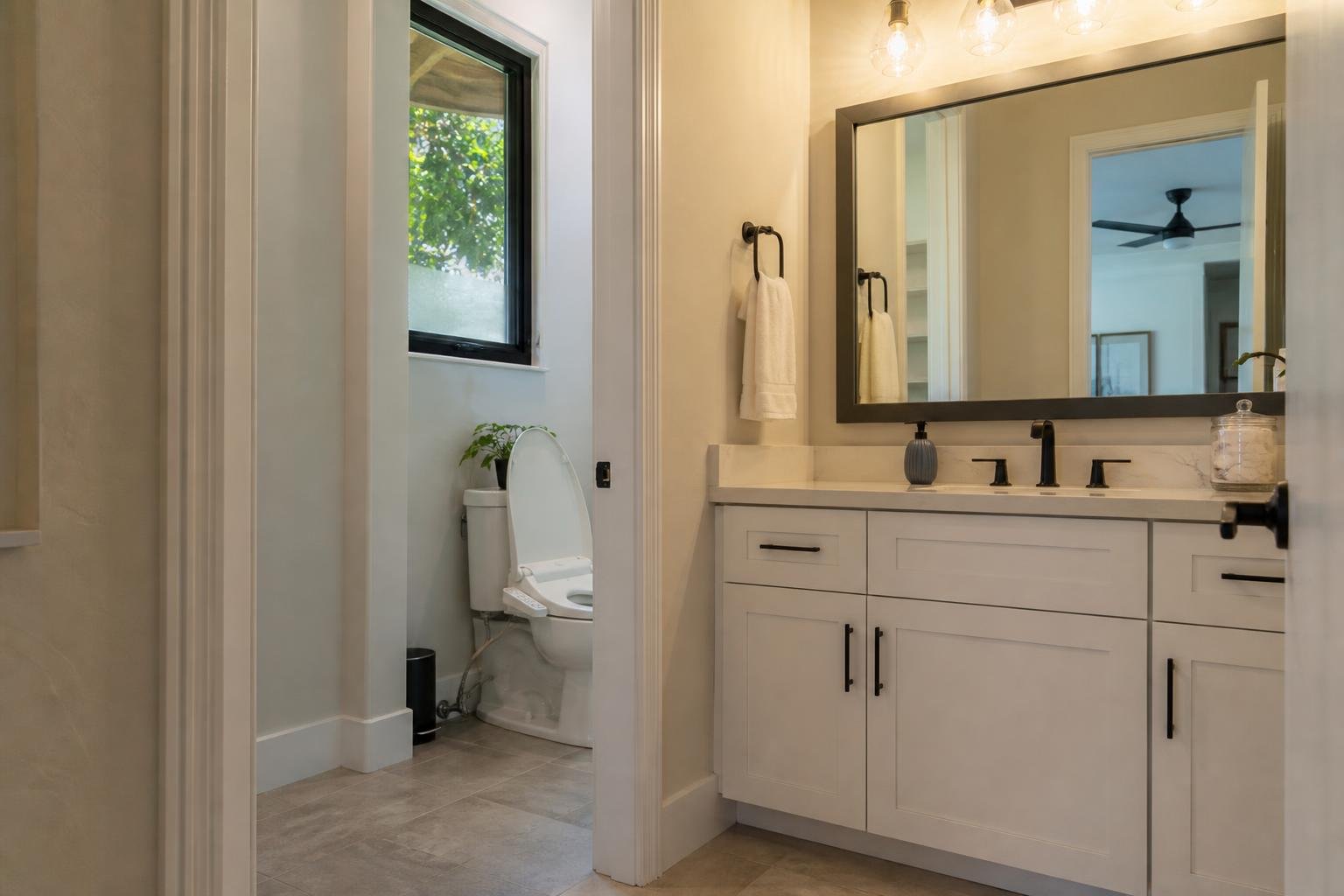 A clean modern bathroom vanity and toilet area in a Florida home with a bidet seat installed, tile flooring, warm natural light through a window, no readable text, no brand logos, no people's faces