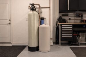 A residential water softener system with a brine tank and resin tank installed in a Florida garage utility area, clean and organized, soft overhead light, no readable text, no brand logos, no.