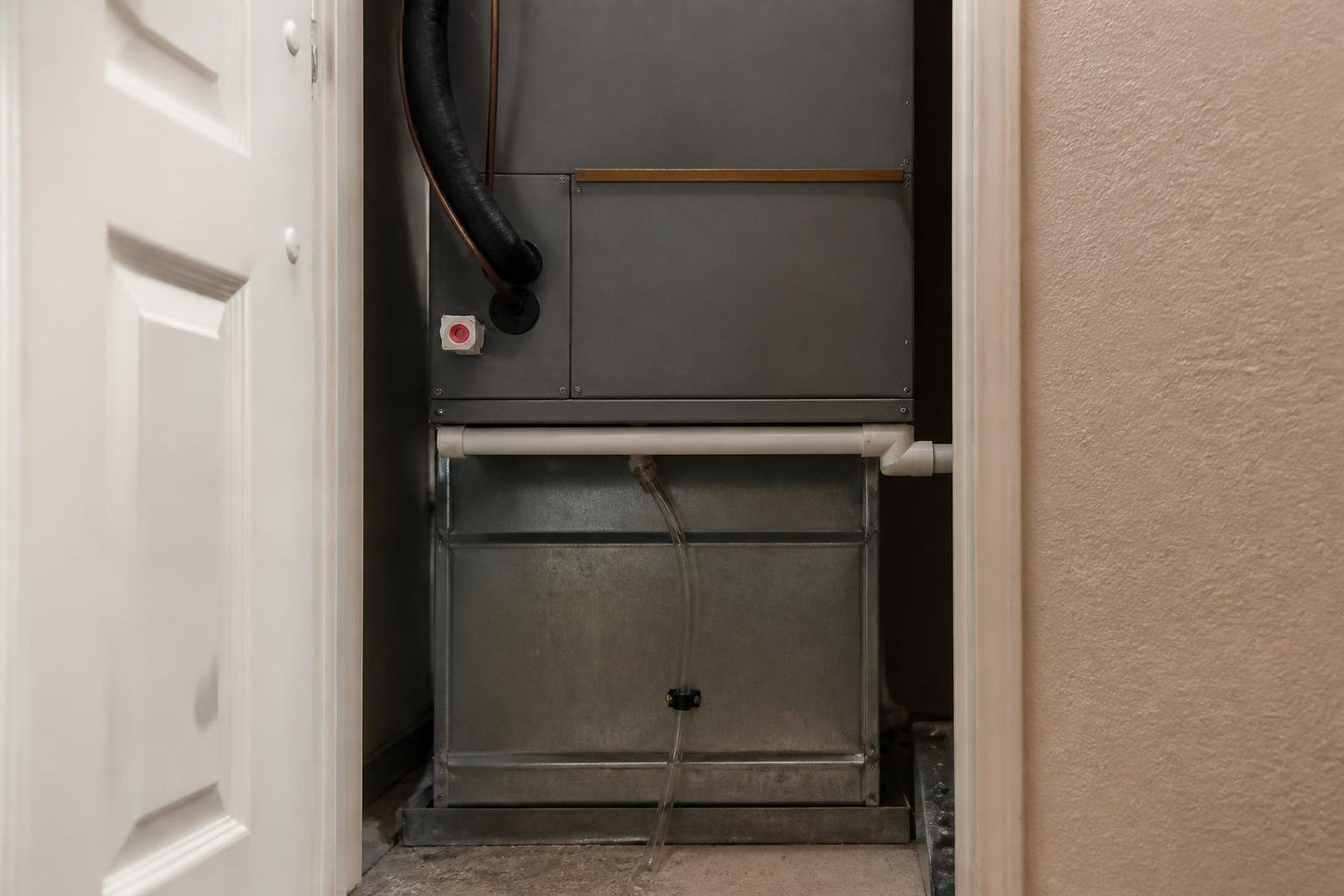 A clear condensate drain line running from an indoor air handler in a Florida home utility closet, soft interior lighting, no readable text, no brand logos, no people's faces